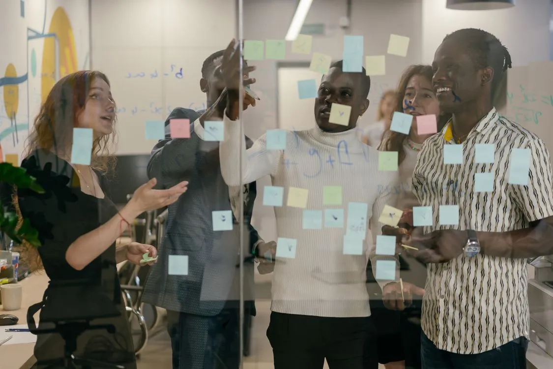 catchy business name ideas - business team brainstorming with sticky notes on a glass wall