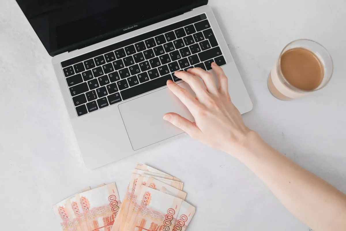 do you have to pay taxes on side hustle income - hand on laptop keyboard with cash and coffee