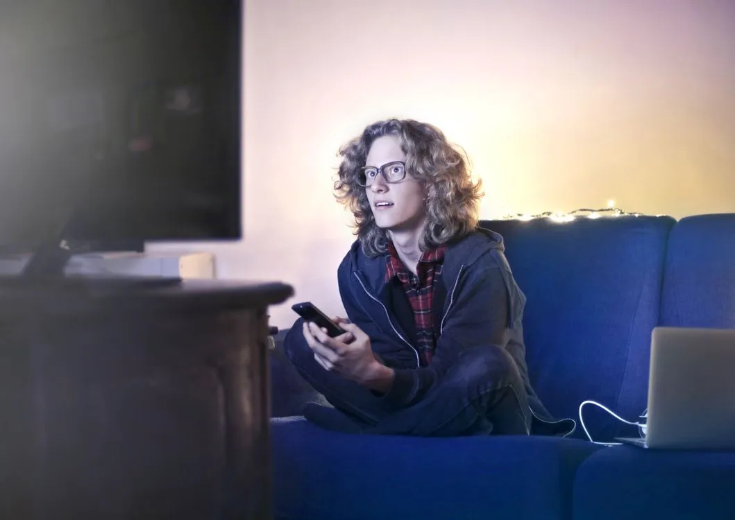 how to cast phone to tv without wifi - person holding phone while watching tv