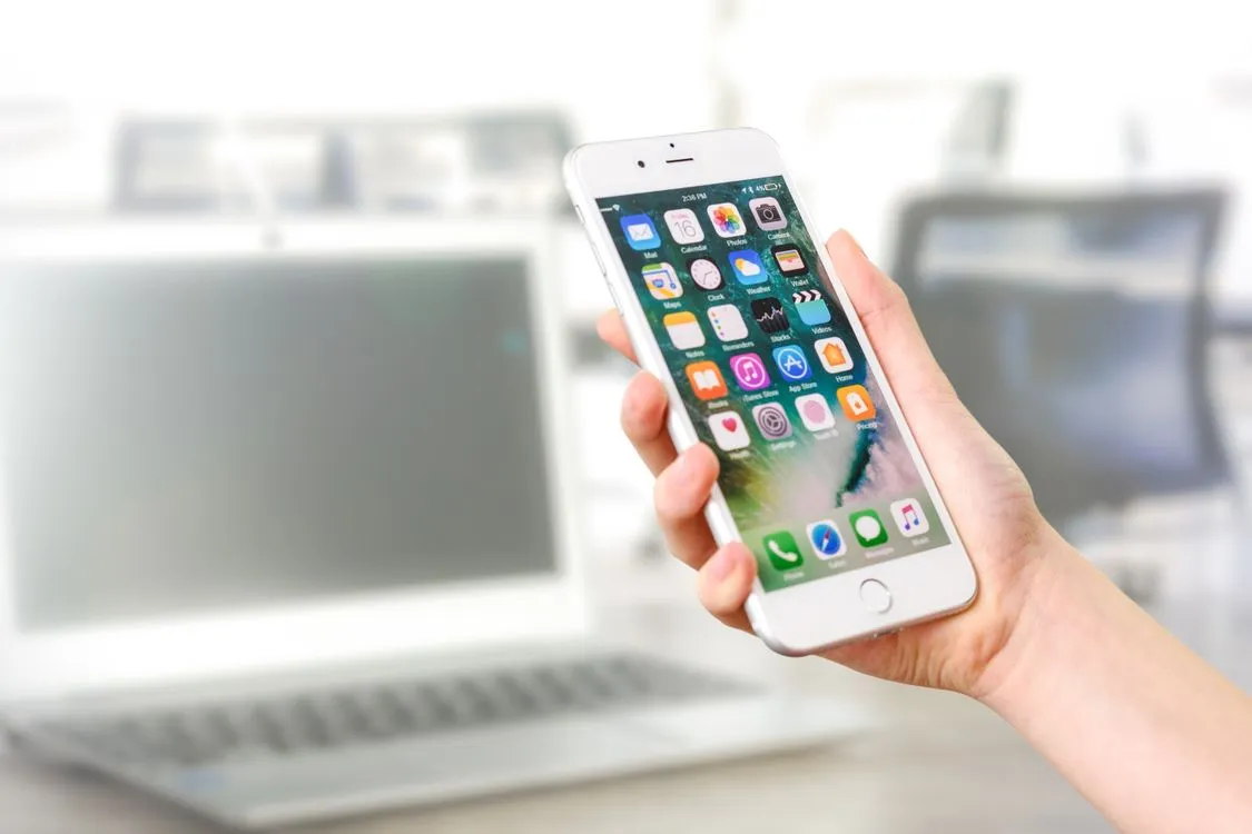 how to permanently delete apps on iphone - hand holding iphone showing home screen app icons