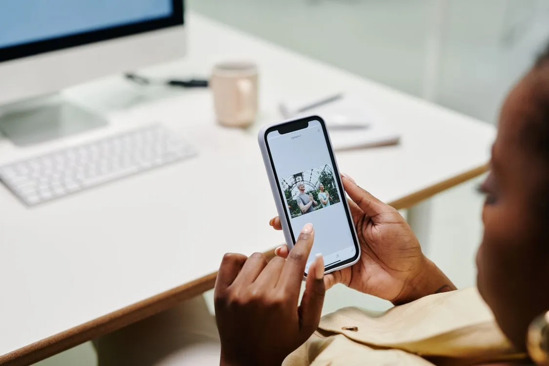 how to recover deleted photos from google photos trash - close-up of hands using a smartphone at a desk