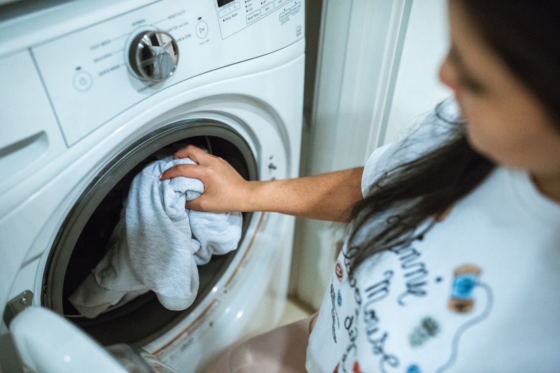 How to deep clean a washing machine — woman loading a front load washer