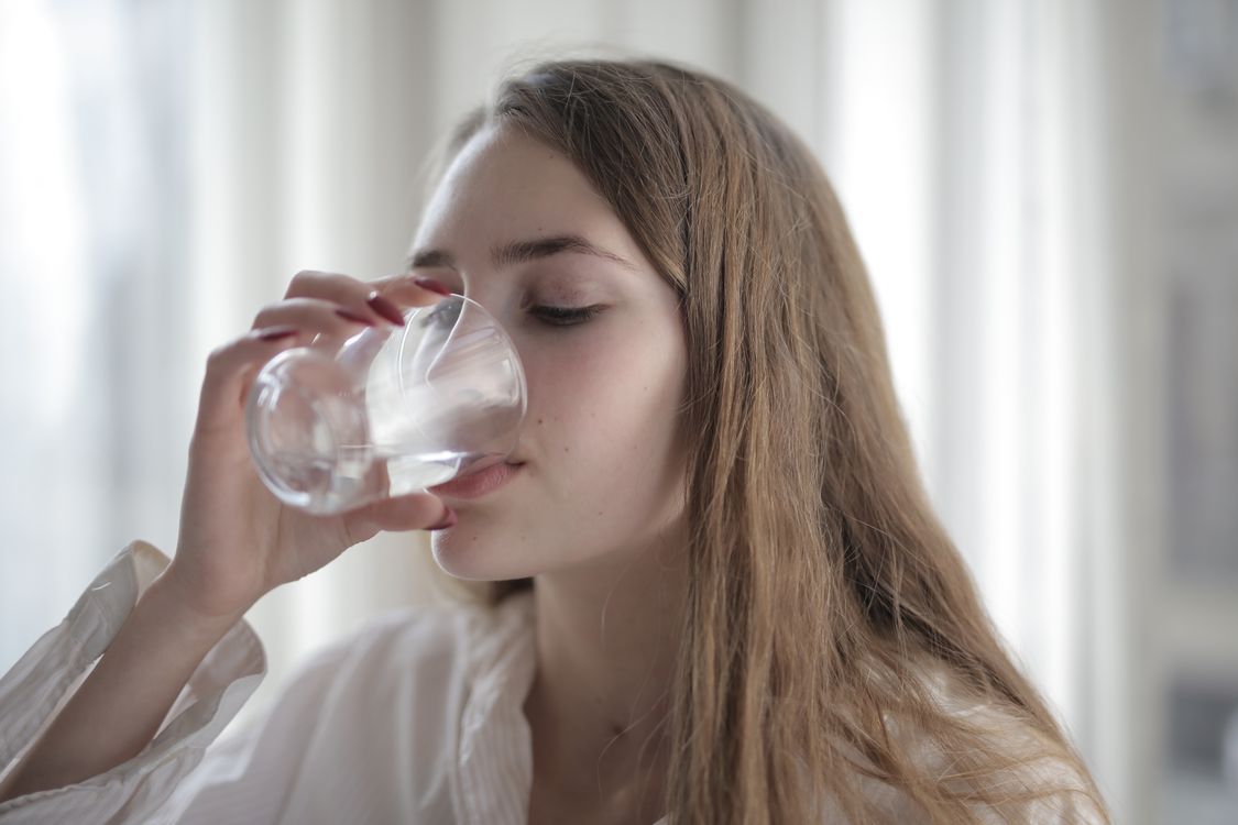 how to get rid of hiccups fast - woman drinking a glass of cold water