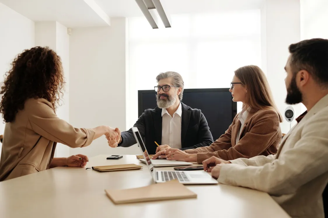 how to negotiate salary for first job - colleagues celebrating a successful negotiation with a handshake in an office