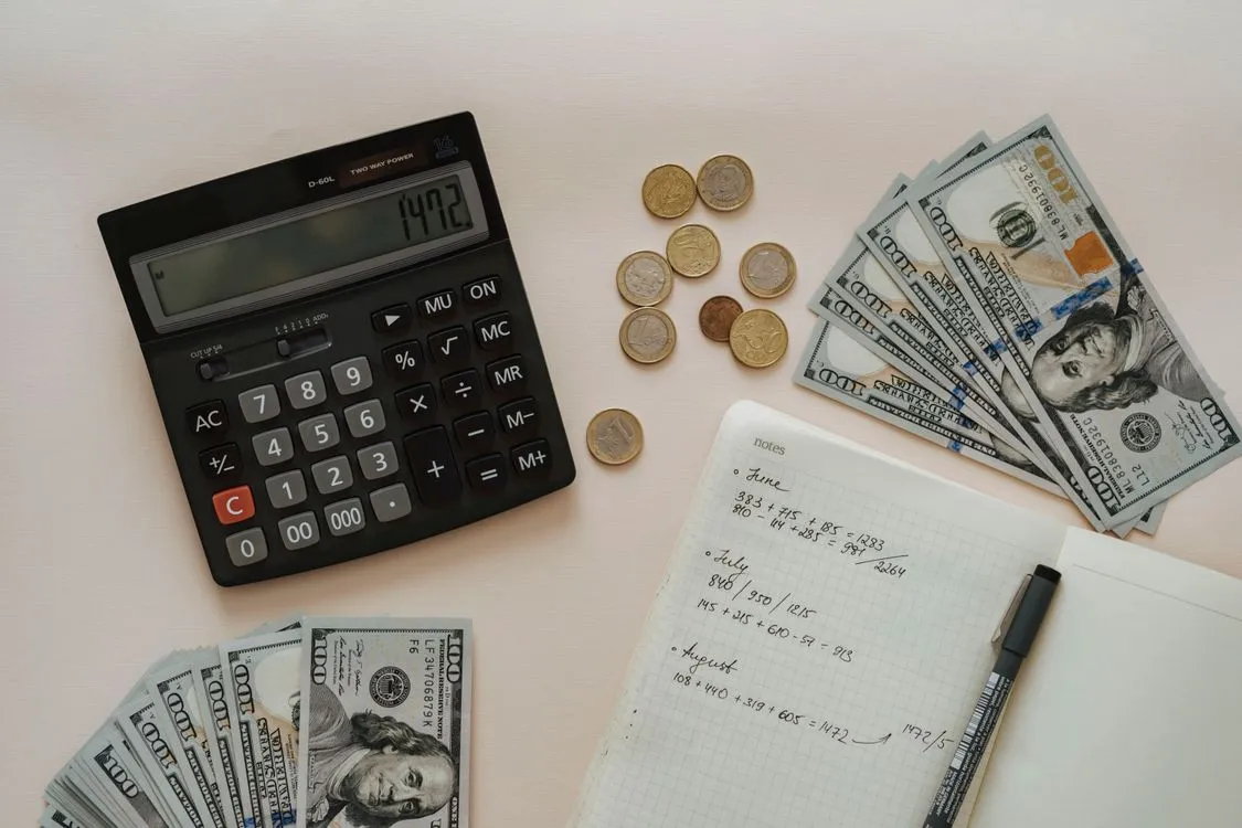 how to price freelance work as a beginner - calculator, cash, coins and notebook flat lay for freelance pricing