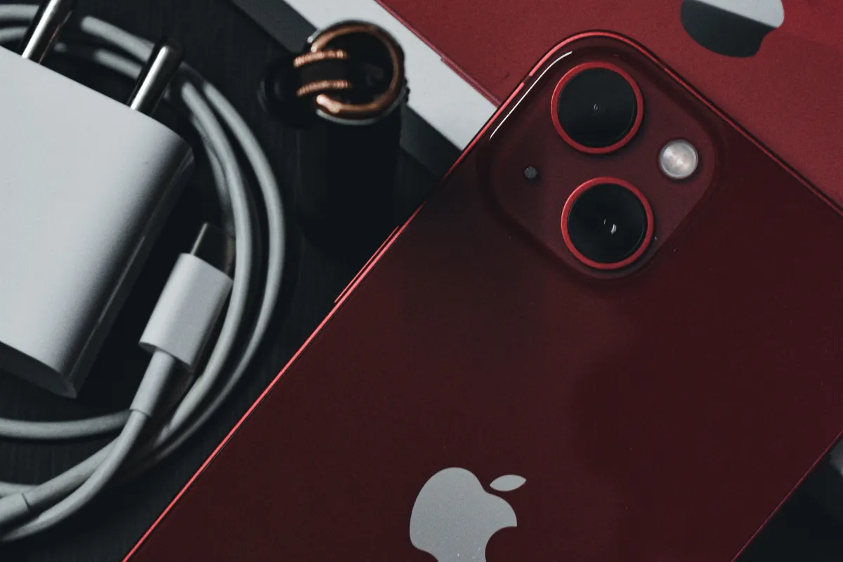 iphone battery draining fast after ios update - red iPhone next to charger and cable