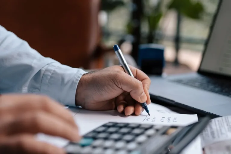 self employment tax rate 2026 - person calculating finances with calculator and paperwork